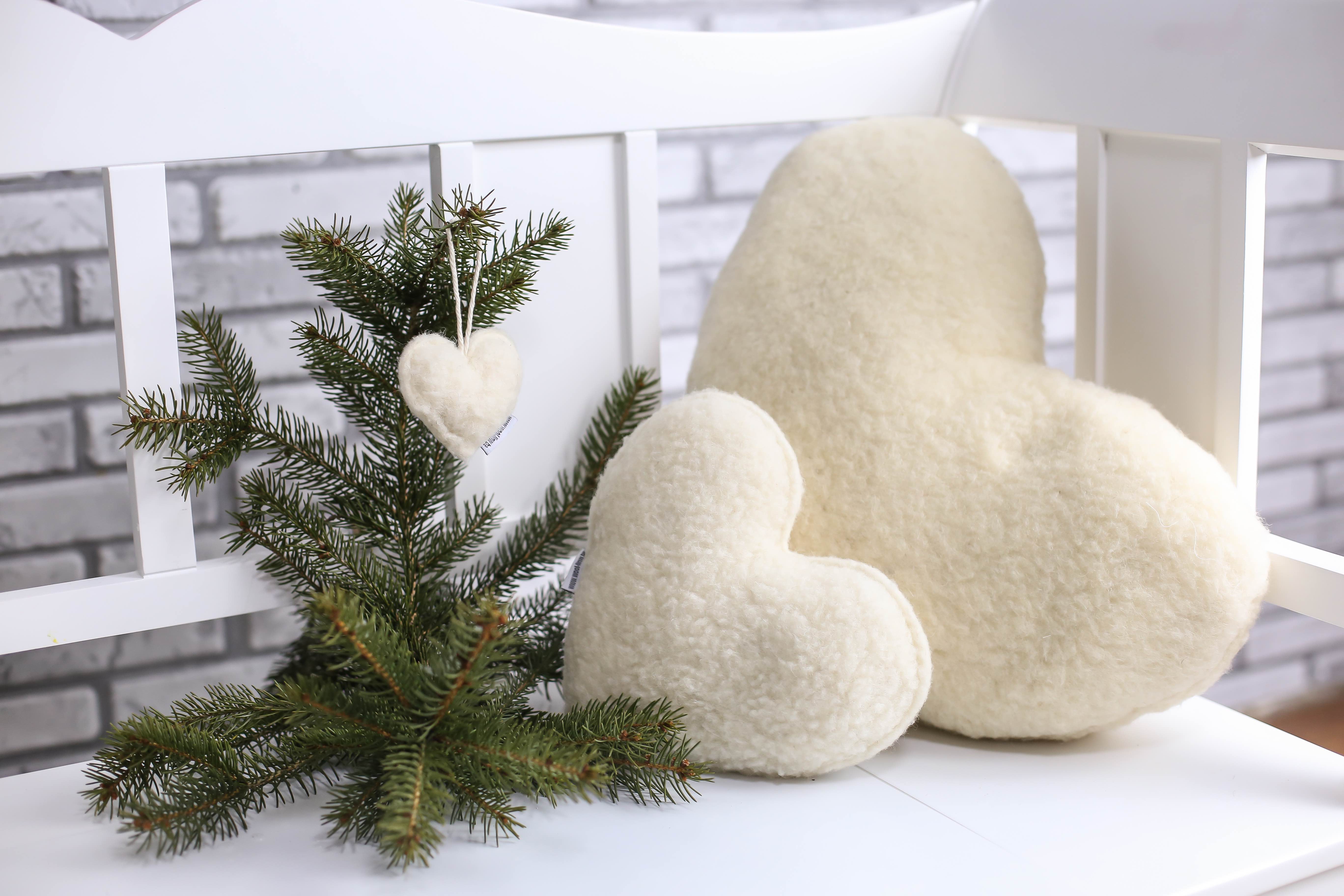 Das Herzkissen in kleiner, mittlerer und großer Größe aufgereiht auf einer weißen Gartenbank.