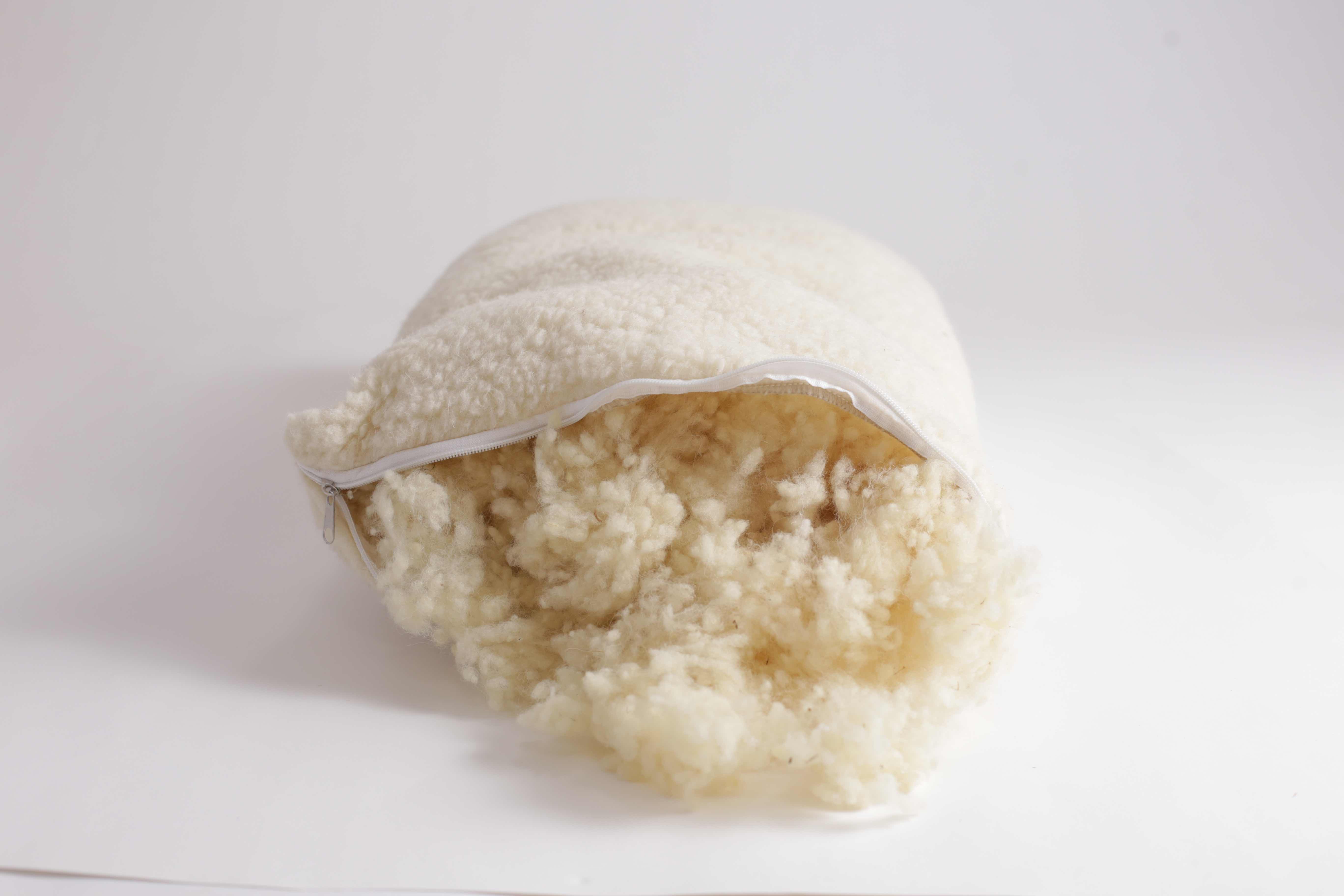 Der Reißverschluss den Kissen Schafschurwolle von Wool-Line steht offen und es kommen die fein geformten Wollkügelchen im Futter zum Vorschein. Auf diese Weise kann Schafschurwolle entnommen oder hinzugefügt werden, um die Dicke des Kopfkissen flexibel anzupassen.