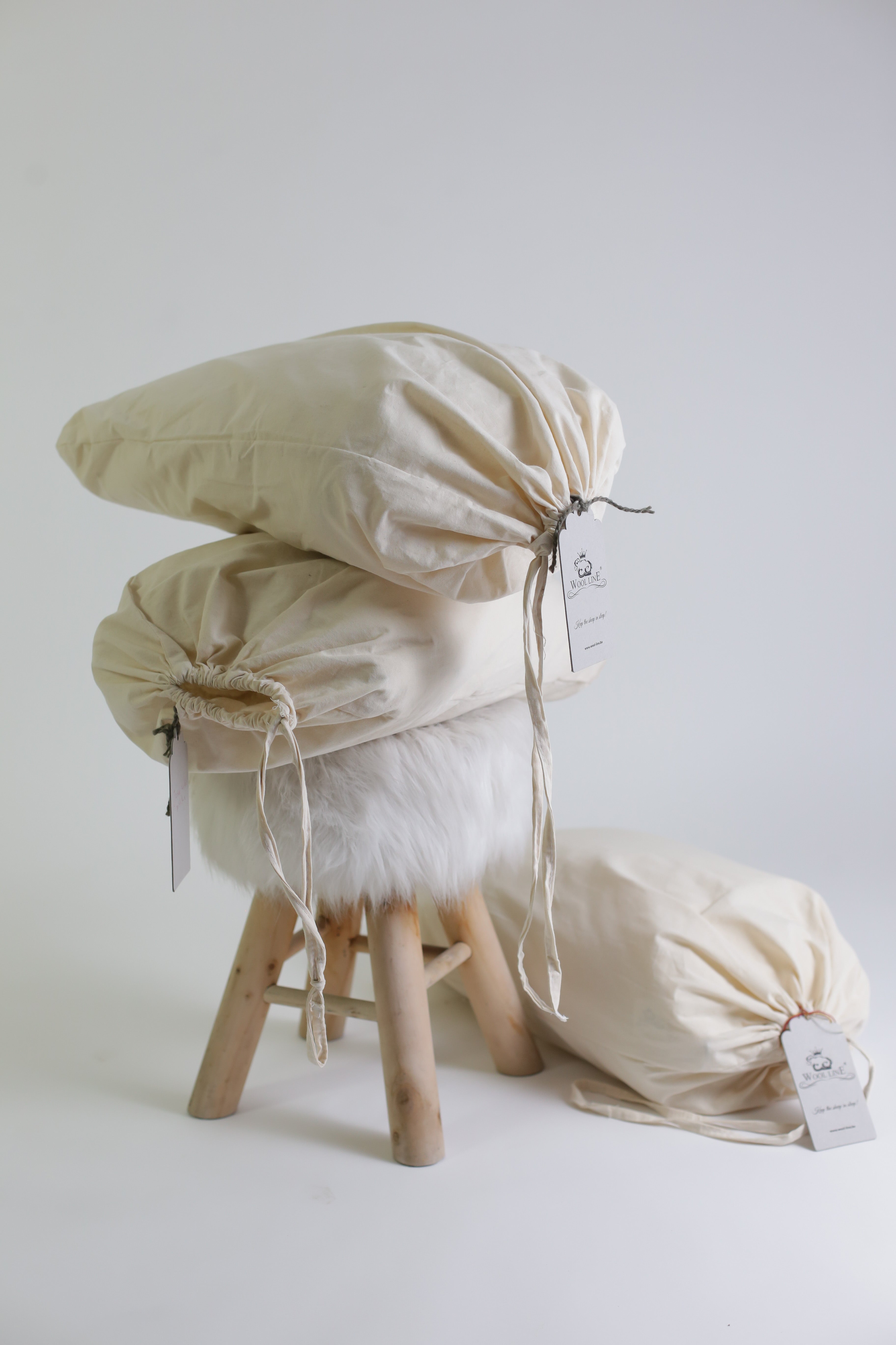 Das Nackenkissen beige Gold dreimal in einem unserer Baumwollbeutel verpackt und bereit zum Versand. Die Lieferung der Nackenrolle erfolgt mit Wool-Line komplett plastikfrei.