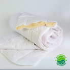 Eine weiße Bettdecke aus Bio-Schurwolle von Wool Line eingerollt auf weißem Untergrund. An der Spitze der Rolle kann man einen Teil der Wollfüllung erkennen. Unten rechts befindet sich ein Siegel, auf dem steht: Eco Friendly 100% Organic, was die nachhaltigen Materialien der Bio-Bettdecke bestätigt. 