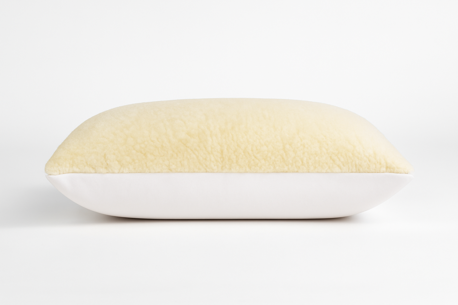 Das Wool-Line Gold/Lux Kissen mit Schafwolle auf weißem Untergrund. Die Oberseite besteht aus weichem und warmen Filz aus reiner Schafschurwolle, die Unterseite ist mit sanfter Bio-Baumwolle überzogen. 