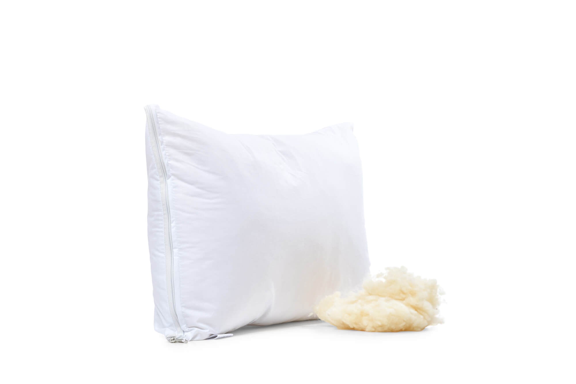 Das Lux-Kissen mit Schurwolle aufgestellt auf weißem Untergrund. Am rechten unteren Ende liegt ein Knäuel feinster Schurwolle, die bei Bedarf flexibel in das Kissen hineingefüllt oder entfernt werden kann. 