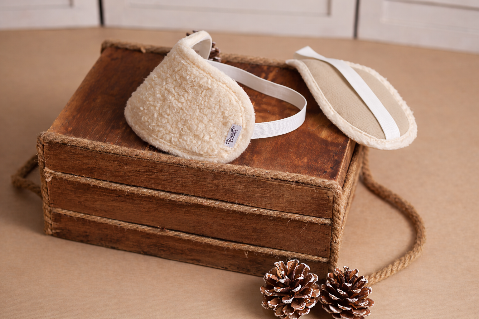 Zwei Schlafmaske Bio auf einer kleinen Ablage aus dunkelbraunem Holz. Links ist die Außenfläche aus Bio-Baumwolle zu sehen, während der feine natürliche Wollfilz aus Schafschurwolle auf der anderen Seite zum Vorschein kommt. 