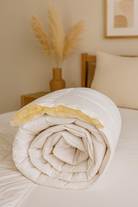 Die Schurwolle Bettdecke Lux von Wool-Line eingerollt auf dem Bett. An der Oberseite ist die Schurwollfüllung zu sehen. Hier zeigt die Bettdecke Lux ihre ganze Elastizität ohne Dellenbildung in der Hülle. 