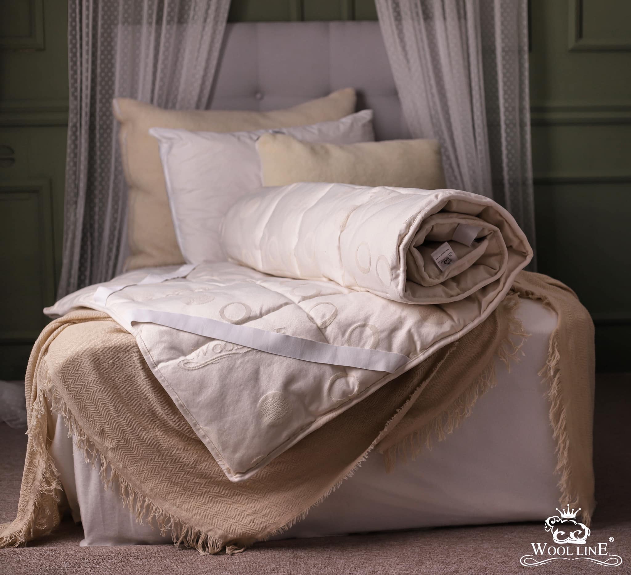 Das Wool-Line Unterbett Schurwolle Lux liegt eingerollt auf einem Bett. Das Futter aus Schurwolle ist 100% natürlich und von handverlesenen Schäfern bezogen und zeigt hier seine ganze Elastizität. 