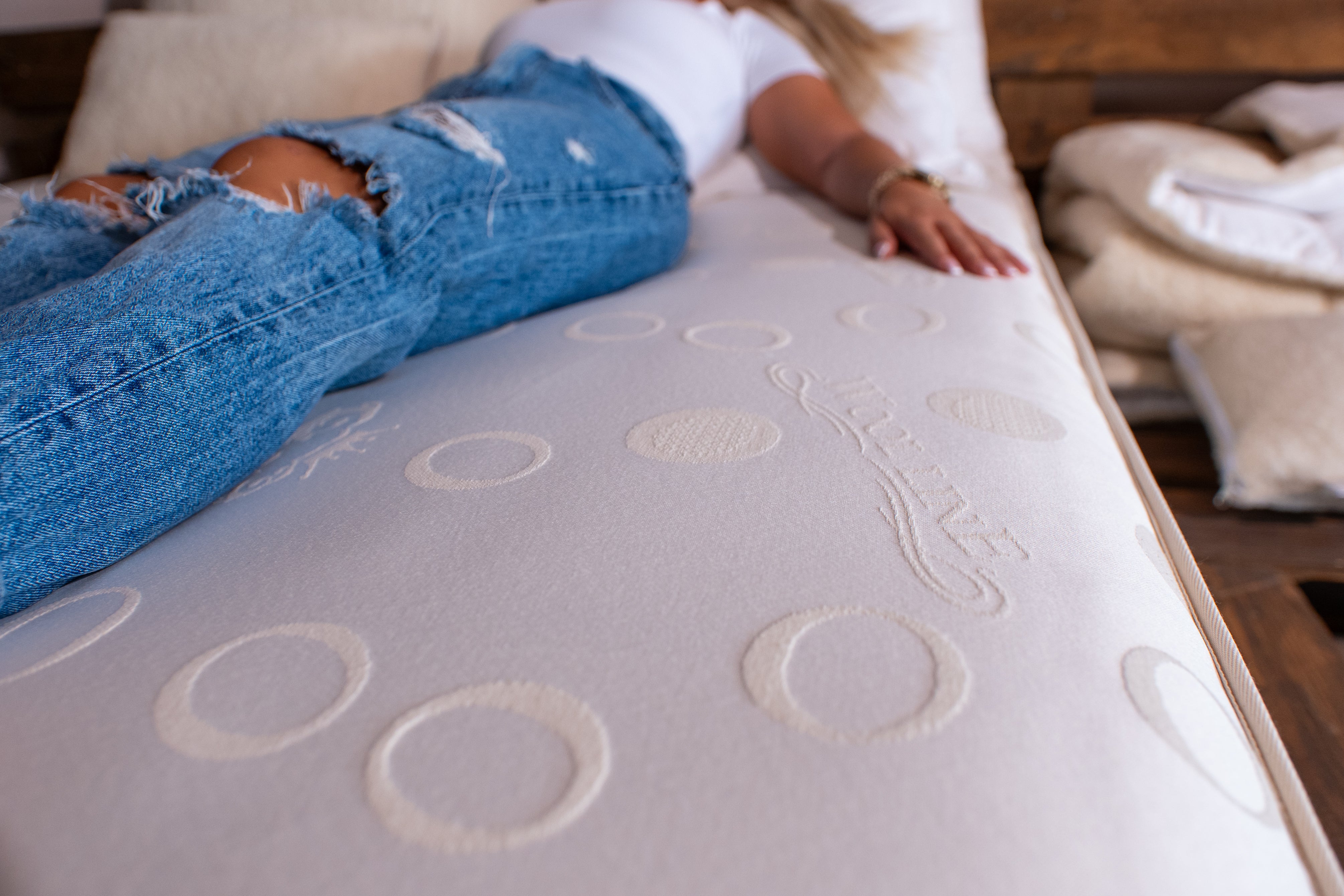 Eine junge Frau lässt sich in einer unserer Matratzen aus Schafwolle fallen. Die Schafschurwolle im Futter macht die Matratze besonders weich und passt sich perfekt ihrem Körper an. 