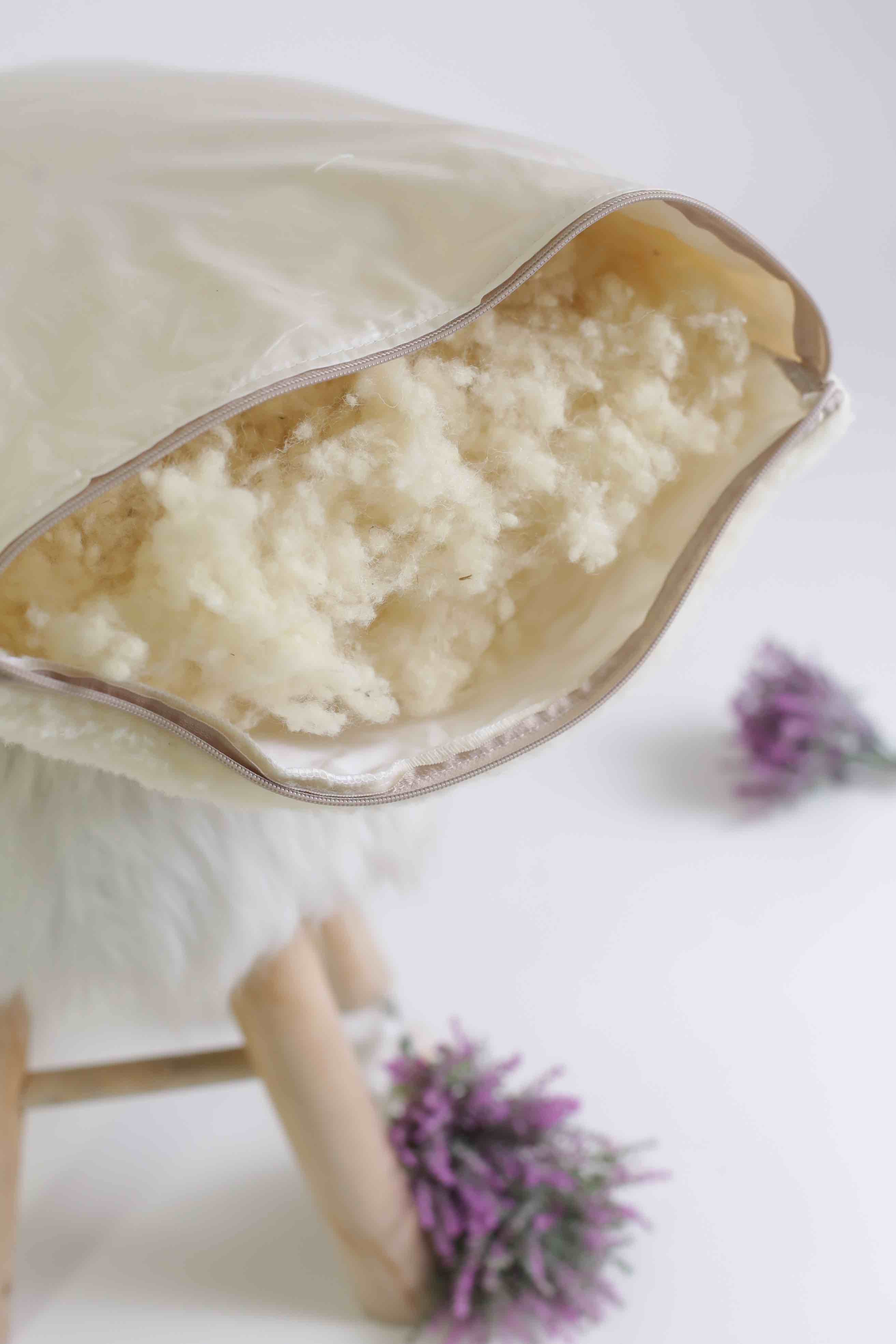 Das Kissen mit Schafwolle Gold/Lux von Wool-Line mit offenem Reißverschluss. Darin kommt die Füllung aus kleinen Schafwollkugeln zum Vorschein, die flexibel entnommen oder hinzugefügt werden können. Damit kann die Dicke des Kopfkissen flexibel angepasst werden. 