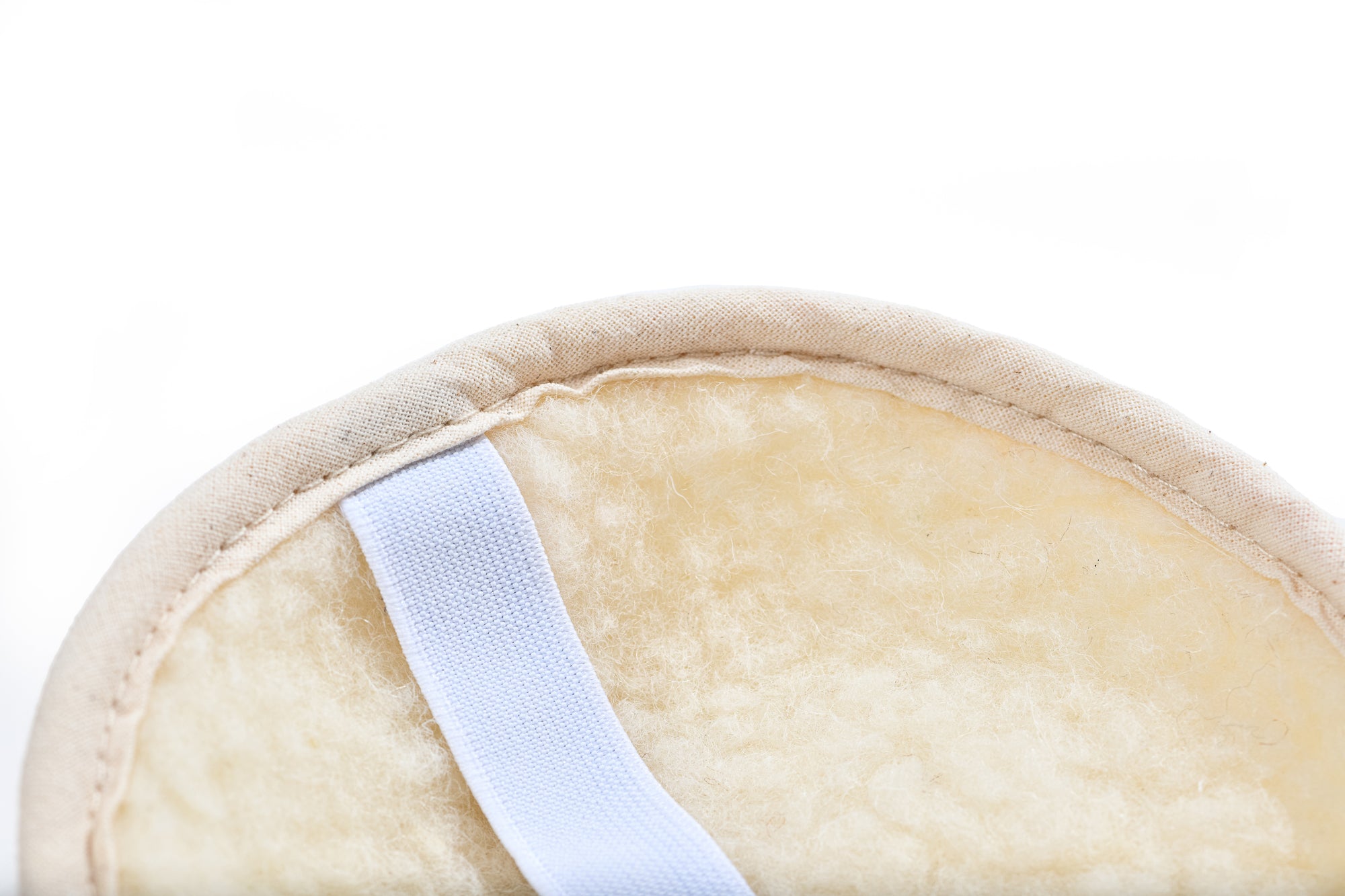 Der Kniegurt von Wool-Line aus Schafschurwolle in der Nahaufnahme. Der fein aufgenähte Filzbezug ist detailliert zu sehen, genau wie Teile des weißen Klettverschluss Bandes, damit der Kniegurt beim Tragen nicht verrutschen kann. 