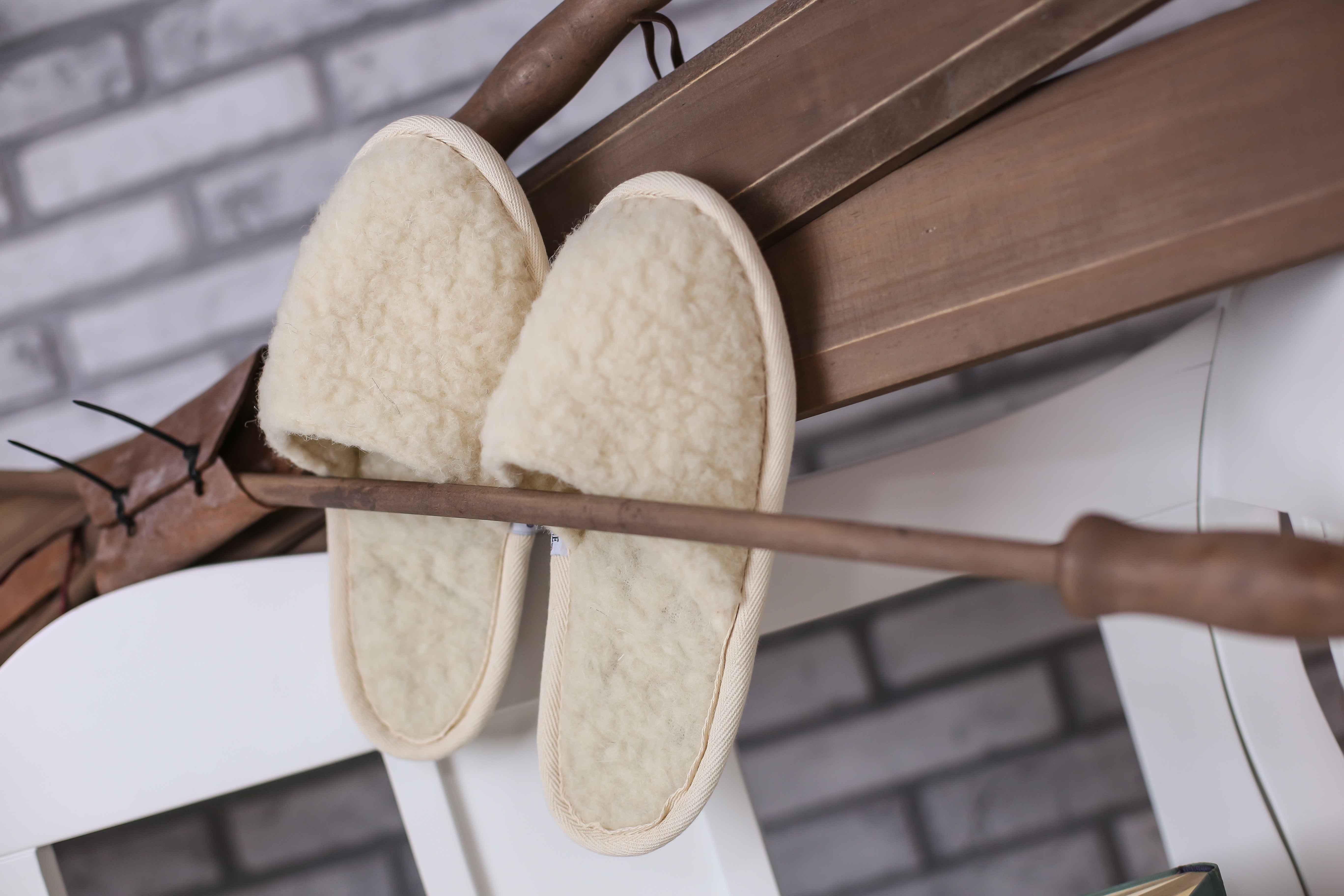 Die Pantoffeln aus Wolle von Wool-Line beim regelmäßigen Auslüften im Freien. Die Wollpantoffeln sind in einem Holzstock eingeklemmt, damit sie während der Selbstreinigung nicht herunterfallen. 
