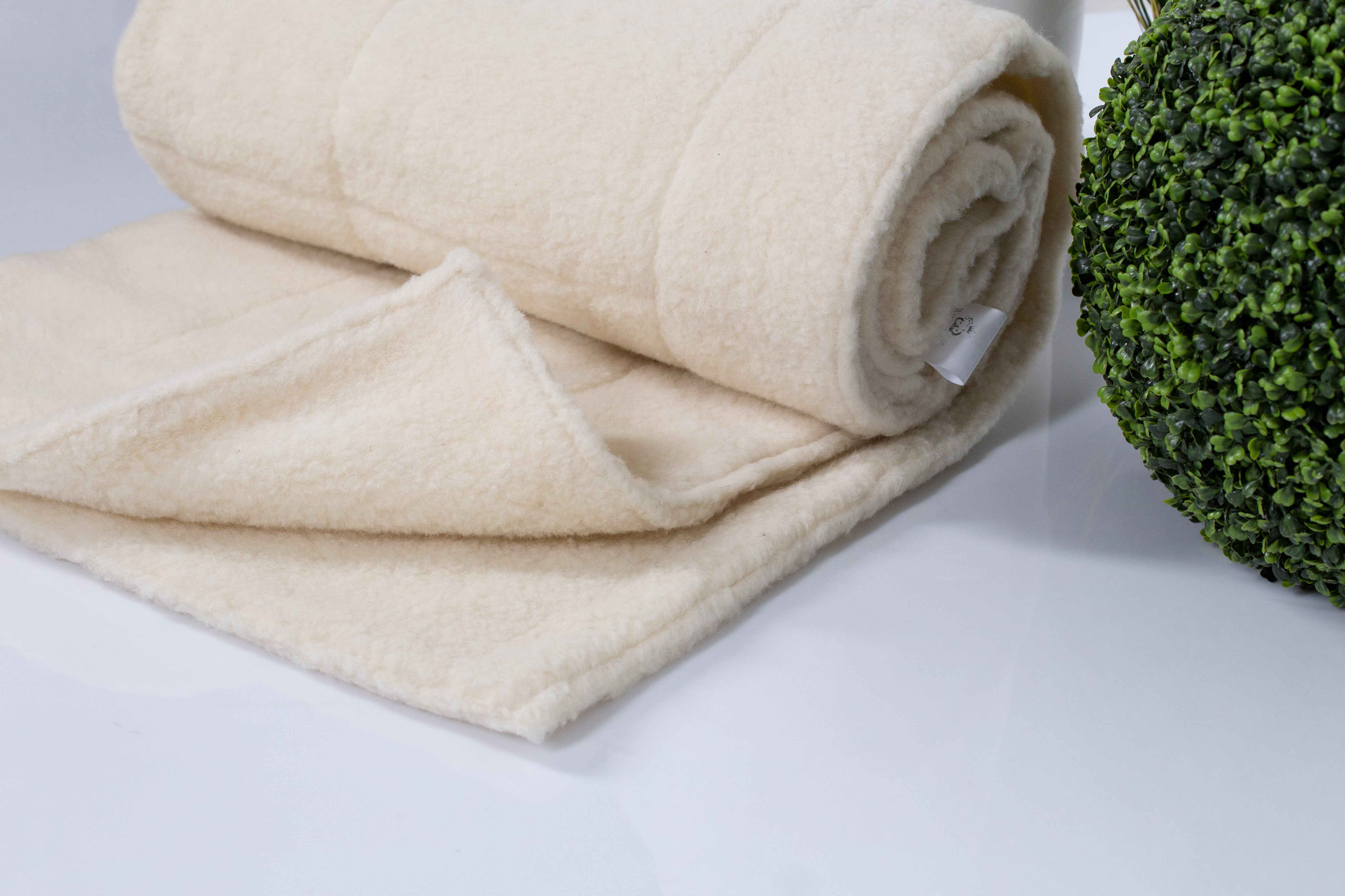 Die Schafschurwolle Bettdecke Gold von Wool-Line eingerollt. Um die Decke zieht sich ein feiner, warmer Filzbezug aus reiner Schafschurwolle. 