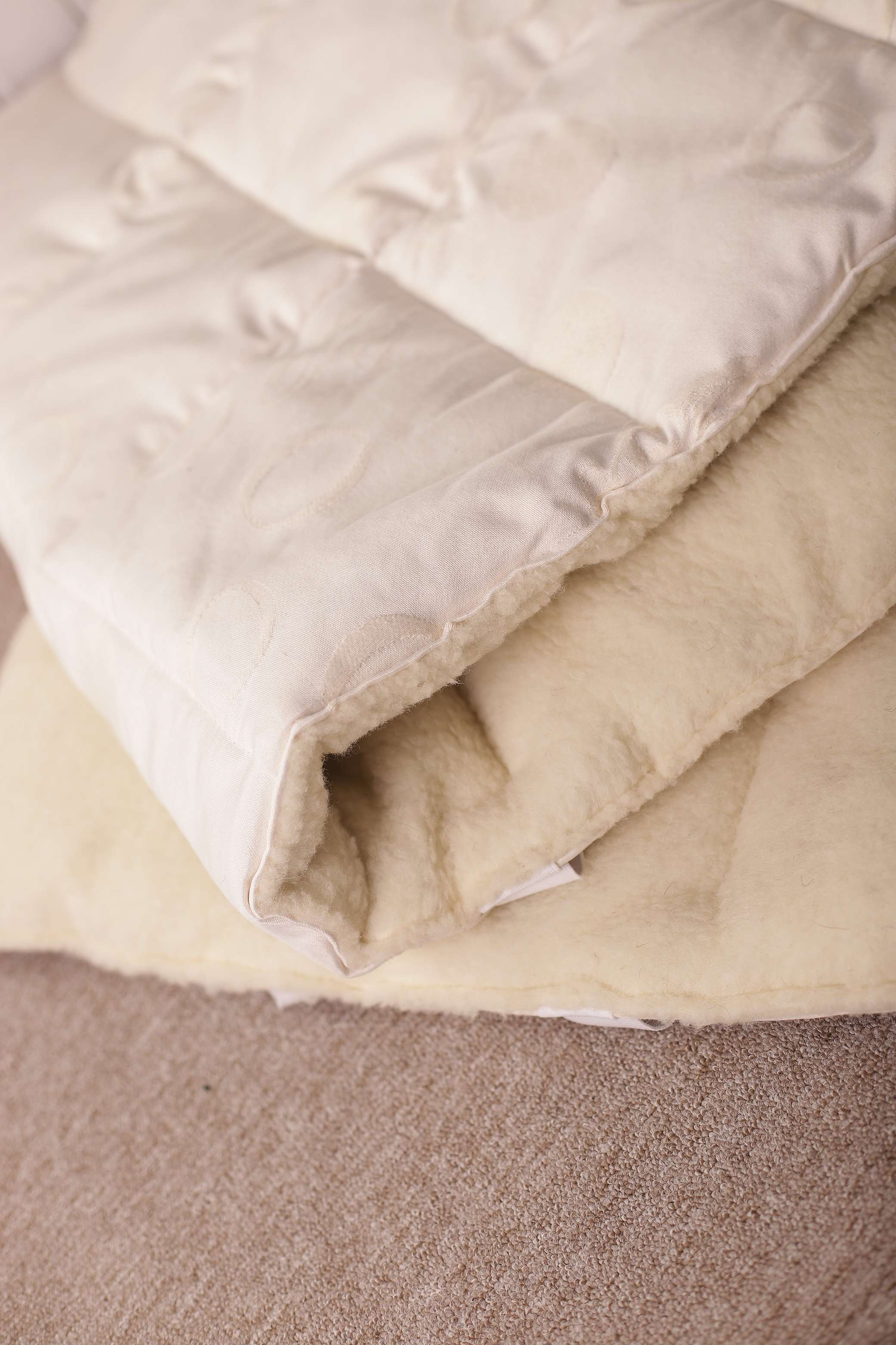 Der Topper Natur Bio von Wool-Line auf dem Untergrund. In der Nahaufnahme ist der weiche Filzbezug aus reiner Schafschurwolle zu sehen. 